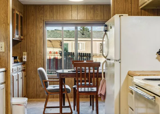 A dining table and chairs at the end of a compact kitchen.