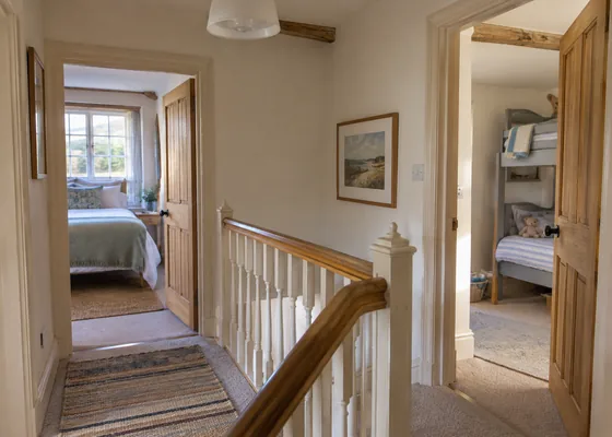 Cottage landing with adjacent bedroom doors.