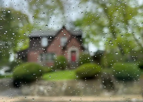 A cottage viewed through raindrops on a window.